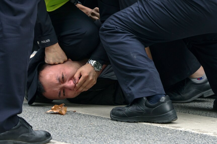 一名男子在上海白纸抗议中被警察按在地上 嘴被捂住