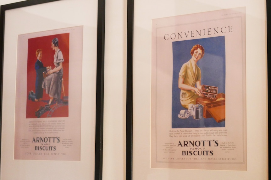 Two A4-sized biscuit advertisements from a magazine, with women holding Arnott's biscuits, framed on a wall.