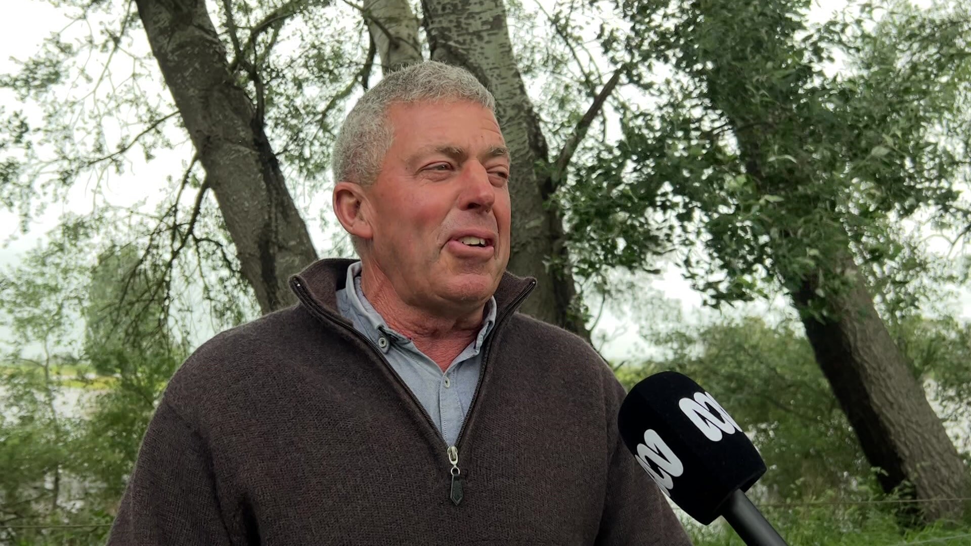 Man in dark jumper outside on his flooded property
