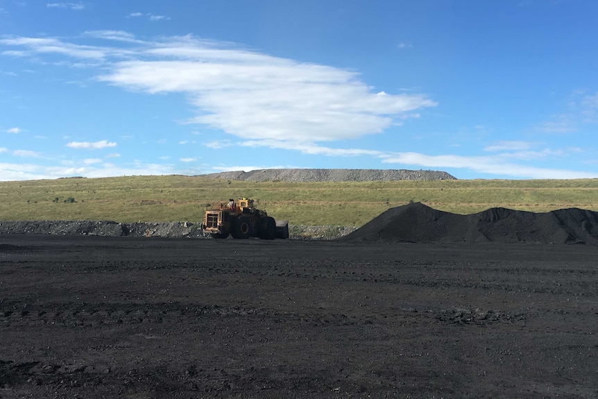 An open cut coal mine with a hill behind.