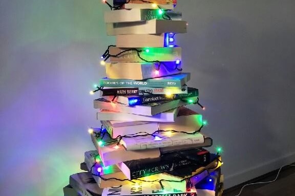 Books piled into a pyramid-like shape, draped in coloured fairy lights.