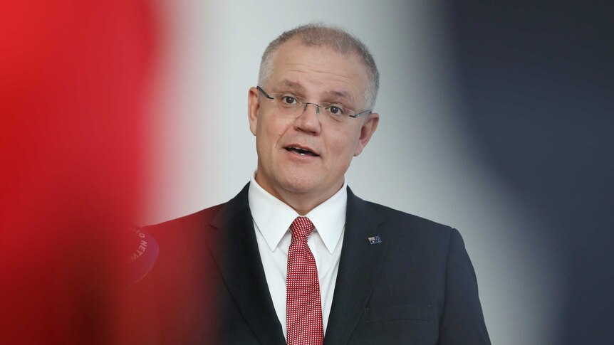 Morrison is talking, wearing a red and white tie and an Australian flag pin.