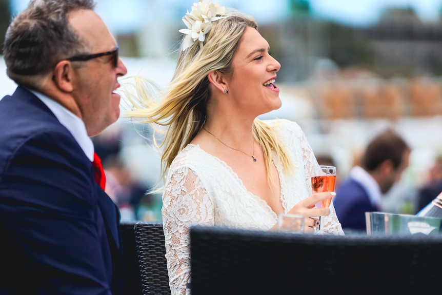 A man and woman sitting down at tables at a race in Randwick