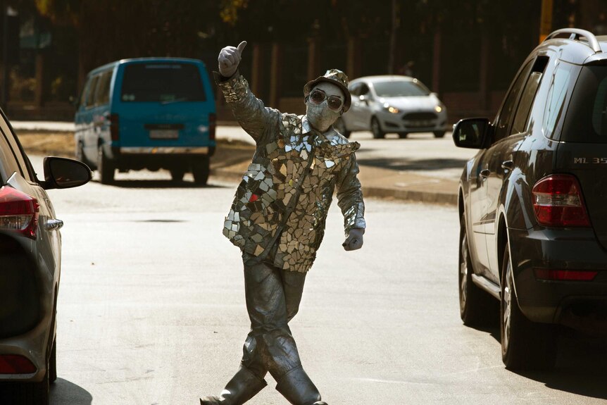 A masked mime artist performs for tips at a busy intersection in Johannesburg.