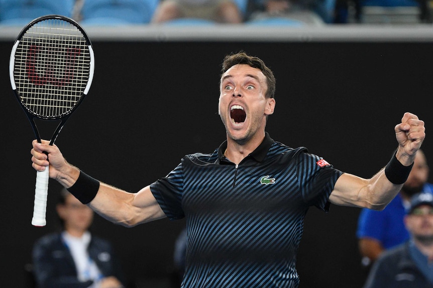 Men's tennis player shouts for joy as he celebrates a win at the Australian Open.