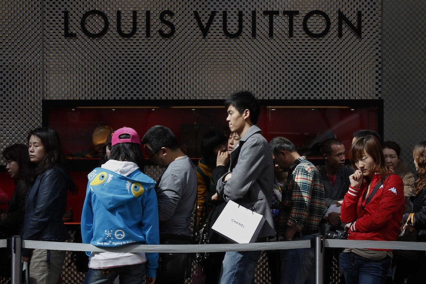 Chinese visitors queue in front of luxury store Louis Vuitton.