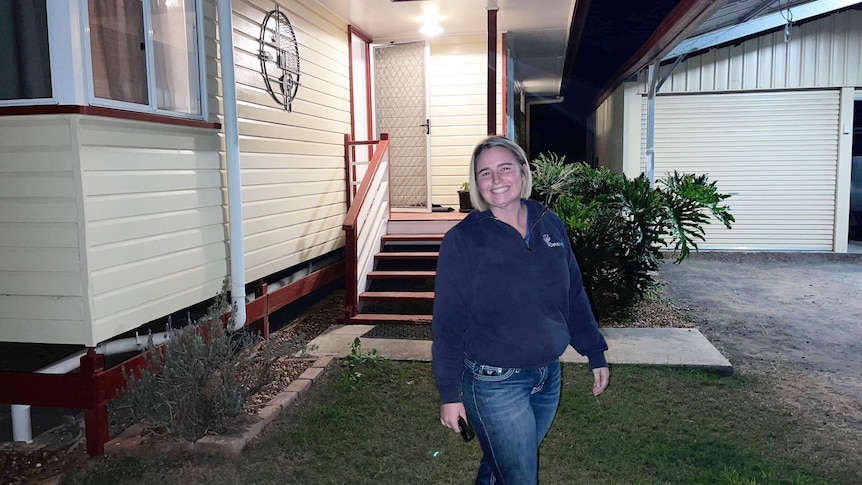 A young woman smiling in front of a house. 