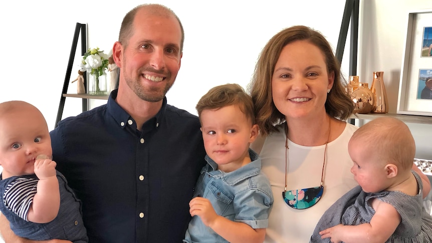 A mother and father hold their three children.