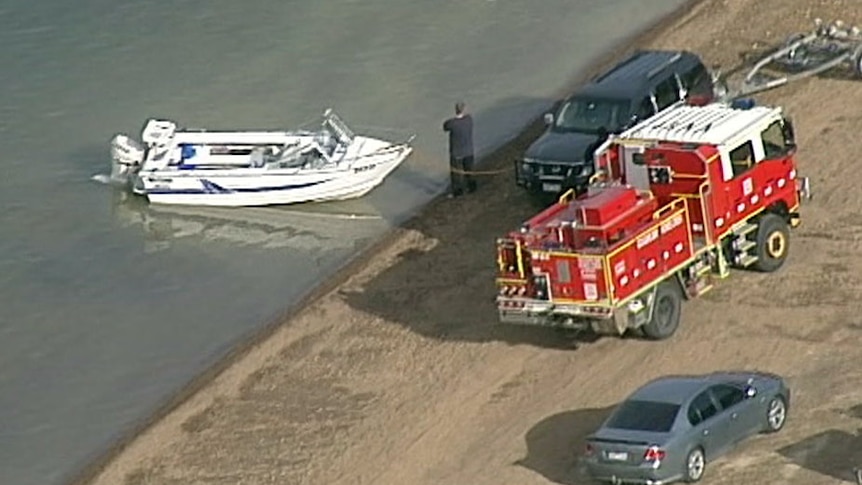 A boat, a vehicle and a fire truck near the edge of the water at Goughs Bay.