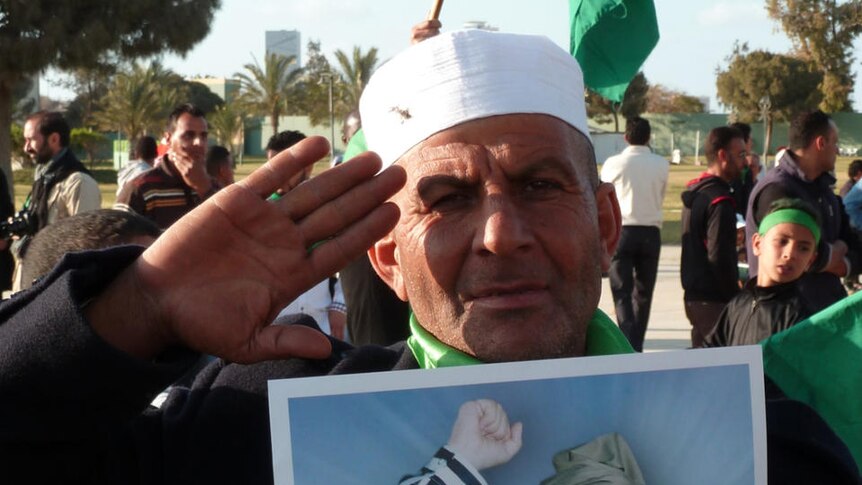 A Gaddafi supporter holds a photo of his leader
