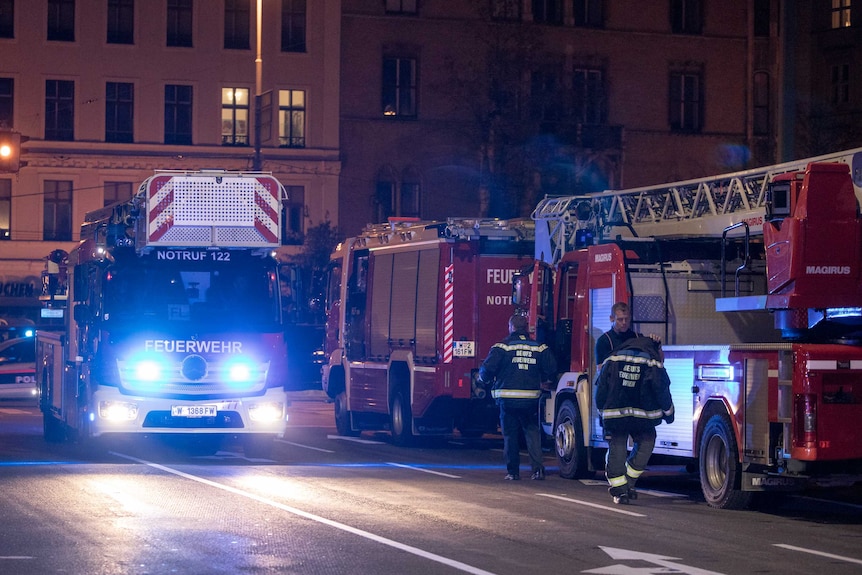 Fire trucks lining the street with firefighters walking alongside it.