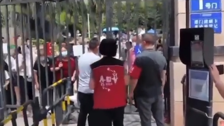 A group of people behind a gate with several people on the other side.