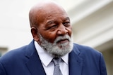 Head and shoulders shot of black man with grey beard wearing suit and tie