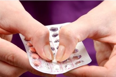 Woman pops out contraceptive pill from package