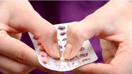 Woman pops out contraceptive pill from package