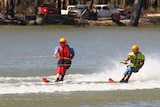 Two men on water skis in a river.