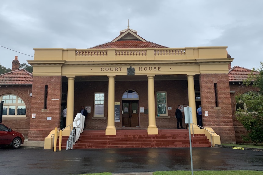 An old red brick and yellow building with the words 'Court House' on the front.