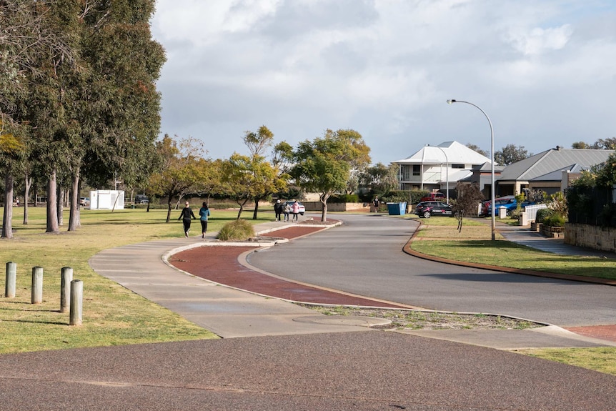 Park and street with houses with women walking along a footpath