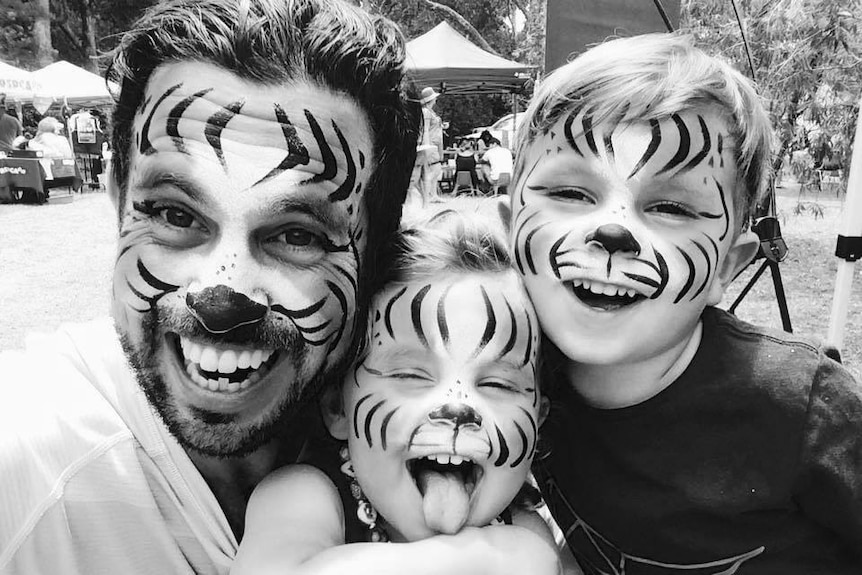 Lach Searle with his two young children with their faces painted like tigers.