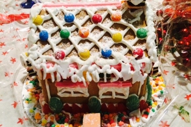 A gingerbread house with lollies and icing sugar 'snow'