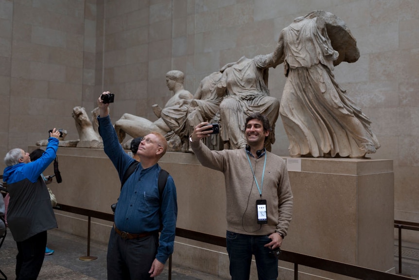 Visitors pose in front of the British Museum's Elgin Marbles that originate from the Parthenon in Athens.