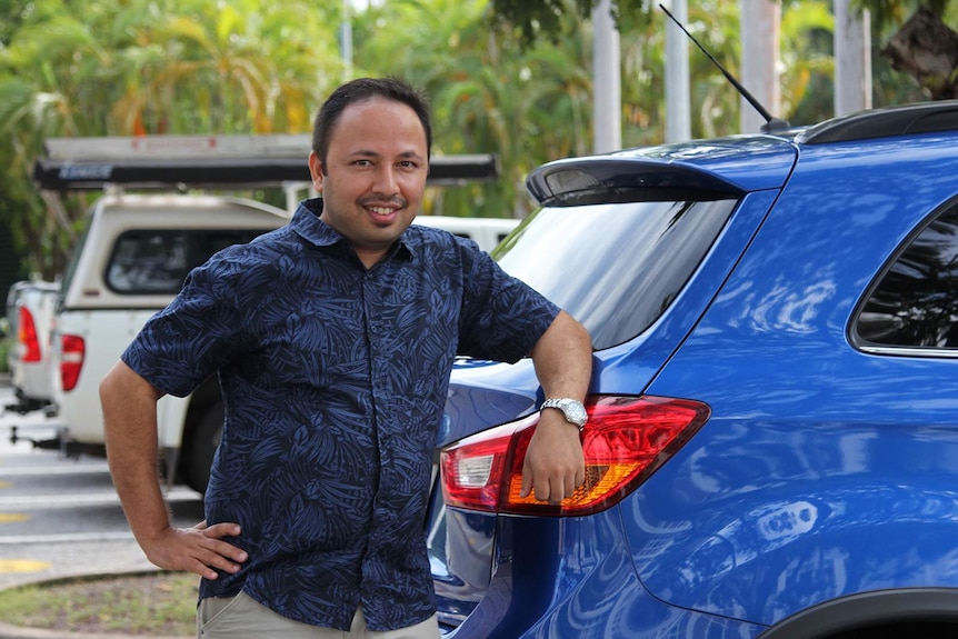 Hi Oscar driver Yogesh Thapaliya leans on his bright blue car.