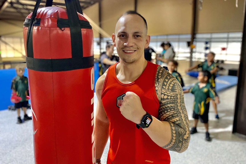 A man smiling with boxing gloves over his shoulder