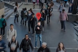 A man stands still on his phone in a crowd as people move around him.