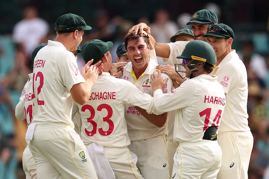 Australian players embrace Pat Cummins after a wicket in the SCG Ashes Test.