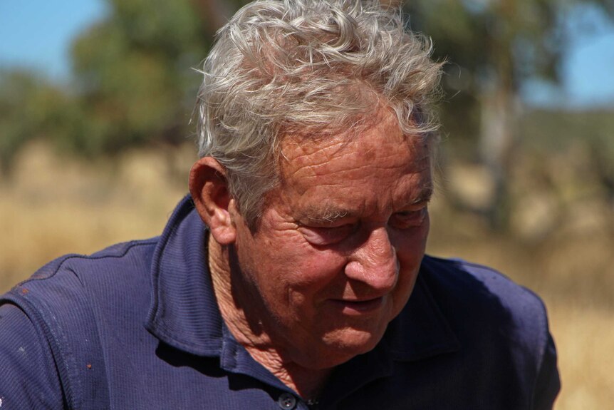 A grey haired man looks at the ground