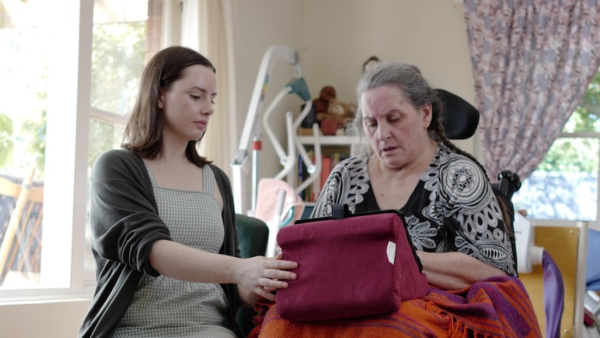 A woman in a wheelchair sitting down with a younger woman