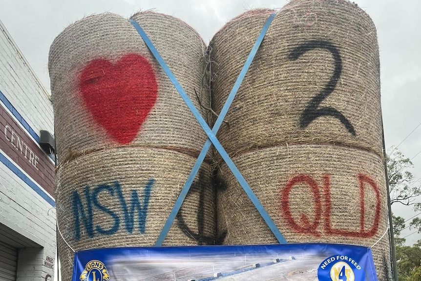 spray-painted hay bales reading "love to NSW and QLD".