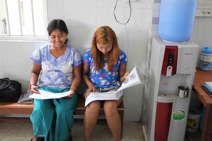 Workers reading handouts on a bench beside a water cooler