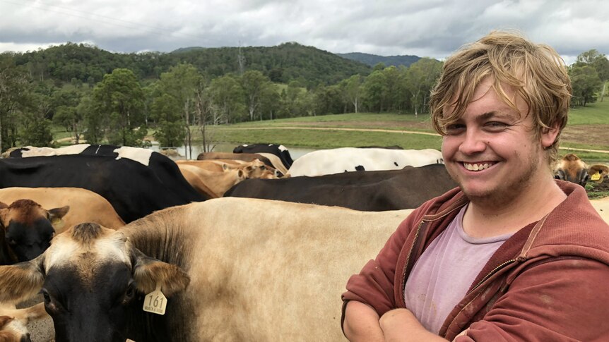 Liam Kirk smiling as the cows eat the food he put in a trough for them.