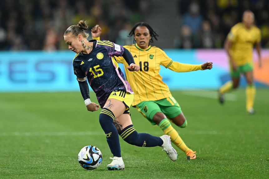 Ana Maria Guzman of Colombia dribbles away from Jamaican players at the FIFA Women's World Cup.