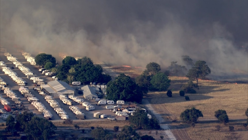 A caravan park right next to flames burning in bushland