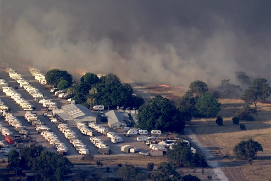 A caravan park right next to flames burning in bushland