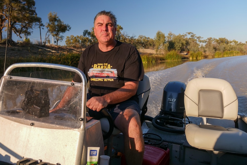 a man looks upstream as he drives his tinnie