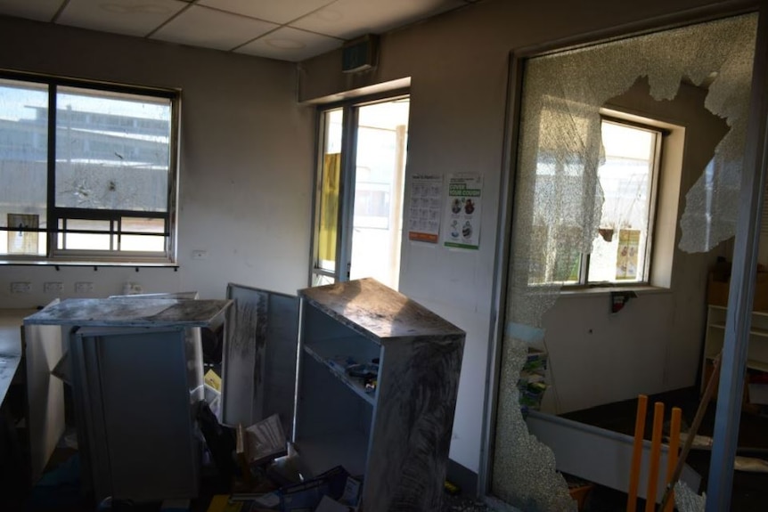 A large glass window inside an office at the prison is smashed, with furniture ransacked.