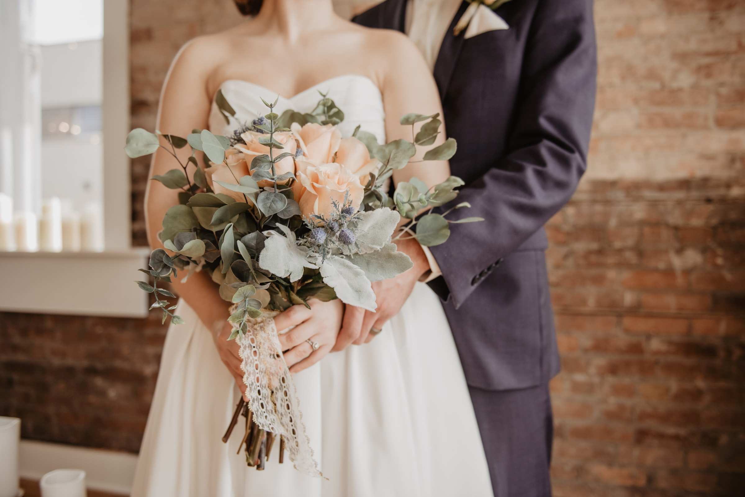 Bride holding flowers, and groom, faces obscured.