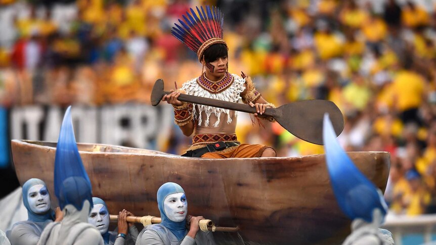 A performer is carried in a canoe during the 2014 World Cup opening ceremony.