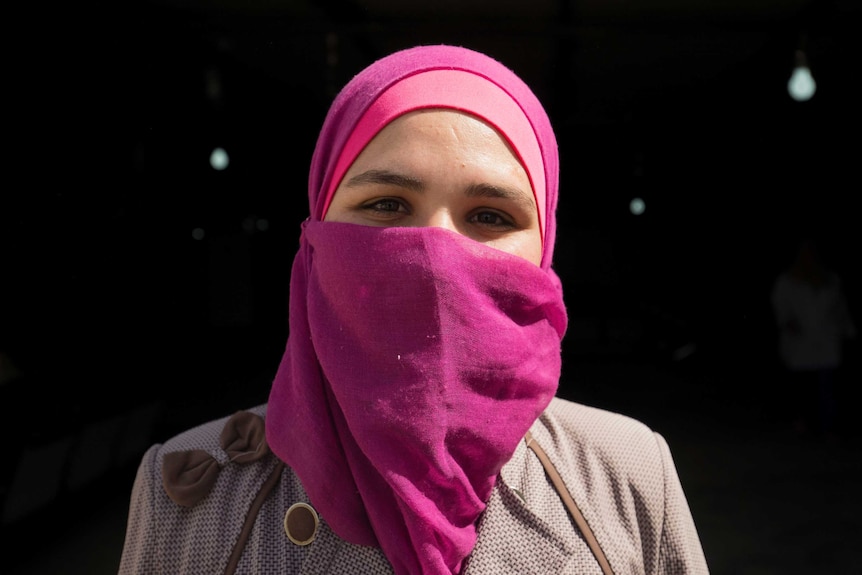 Amal wears a pink headscarf and looks at the camera.