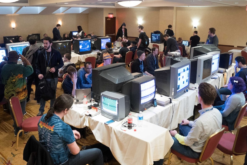 People sit in a room with many televisions and videogame consoles