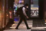 A live export ship crew member with a backpack and face mask on walks away from a Transperth bus at dusk towards a hotel.