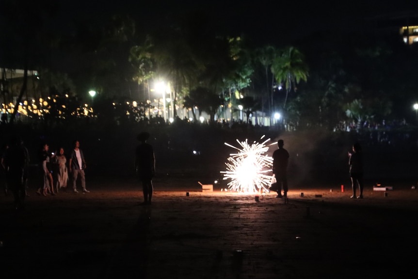 A group of people letting off fireworks on a beach at night