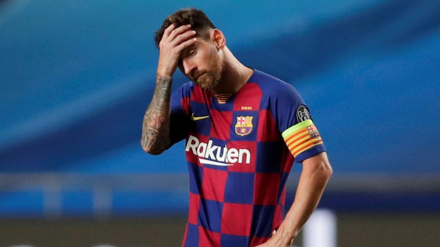 Lionel Messi holds his hand to his forehead as he stands on his own