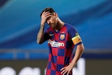Lionel Messi holds his hand to his forehead as he stands on his own