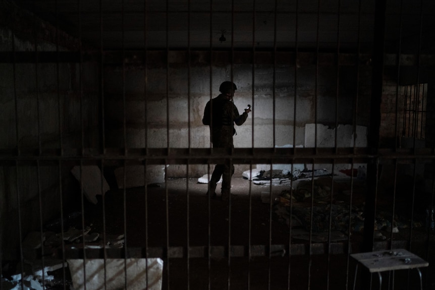 Ukrainian serviceman stands in dark basement, lit up by hit torch.