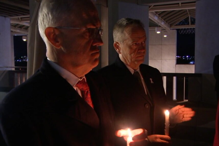 Malcolm Turnbull and Bill Shorten stand together in the dark at Parliament House in Canberra holding candles.