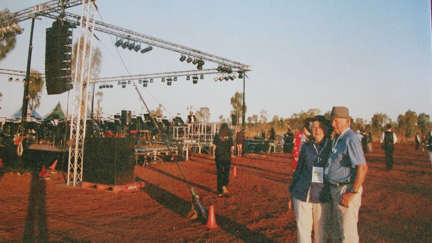 Elvie and Norm Lambert standing near DSO stage set up in red dirt in Northern Territory.